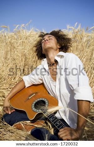 cool guy laying in a cornfield playing guitar