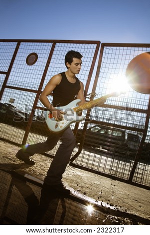 cool guy playing his guitar against sunlight
