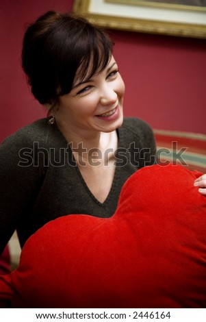 girl holding a heart shaped pillow... valentine\'s day is coming soon
