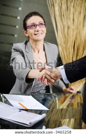 People at work: man and woman hand shaking at a meeting