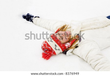 winter scene: blond girl laying down on the snow. Copy space on the left side