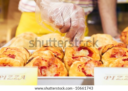 sales clerk in a supermarket picking up a slice of pizza