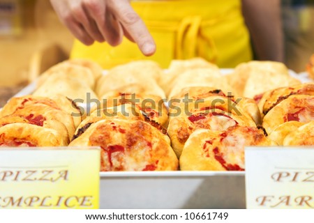 sales clerk in a supermarket pointing a slice of pizza