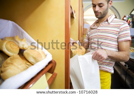 sales clerk in a supermarket putting some bread in a bag. Focus on clerk\'s hand