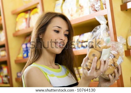woman in a supermarket reading nutrition information and comparing two products