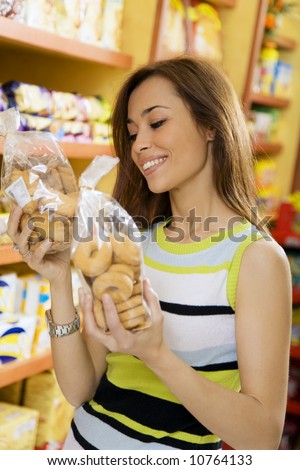 woman in a supermarket reading nutrition information and comparing two products