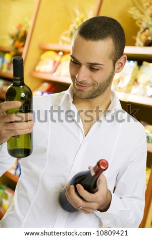 man in a supermarket comparing two wines