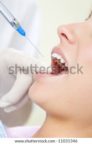 dentist holding a syringe and anesthetizing his patient