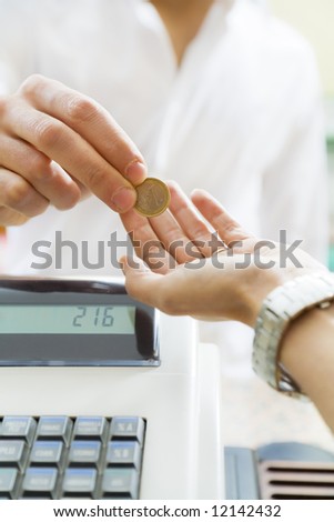 man paying 1 euro to the cashier in a store. Close up of the coin and some copy space