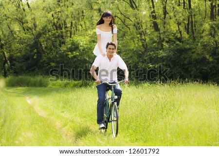 couple biking in park, smiling and hand on shoulders