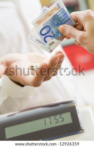 man at the supermarket paying 20 Euro to the cashier