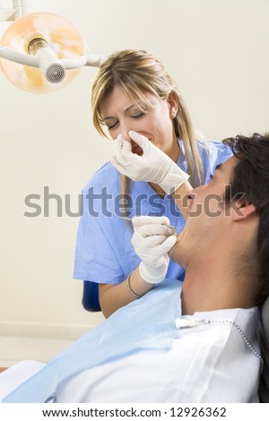 dentist holding her nose and patient with open mouth