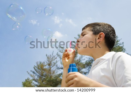 Young boy blowing bubbles in park. Copy space