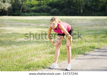 Young blond woman taking breath after jogging