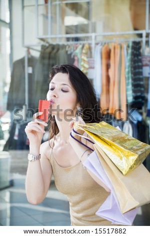 Mid adult Italian woman holding shopping bags and kissing credit card