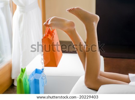 Young woman\'s legs dangling shopping bag