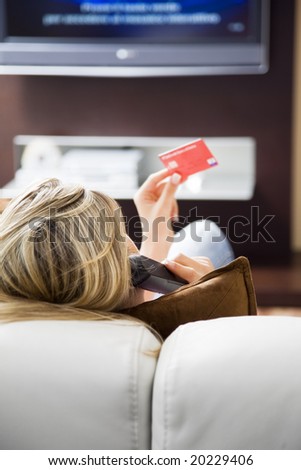 Young woman watching tv and using credit card