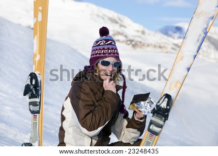 young woman eating chocolate bar on snow