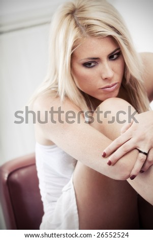 sad woman sitting on sofa with knees bent