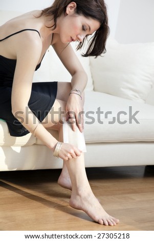 portrait of young woman on sofa having her legs waxed