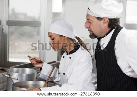 stock photo young chef and mature chef tasting tomato sauce