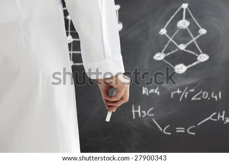 rear view of woman in lab clothes writing chemical formula on blackboard