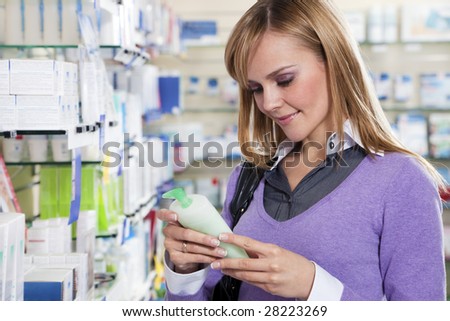 Portrait of blonde woman reading label of shampoo in pharmacy. Copy space