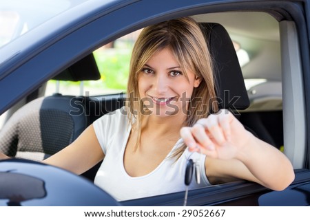 young woman sitting inside car showing keys to new car