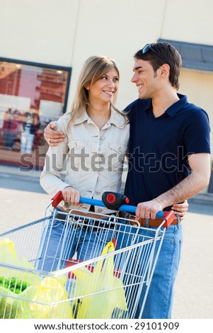 portrait of young couple pushing shopping cart outdoors