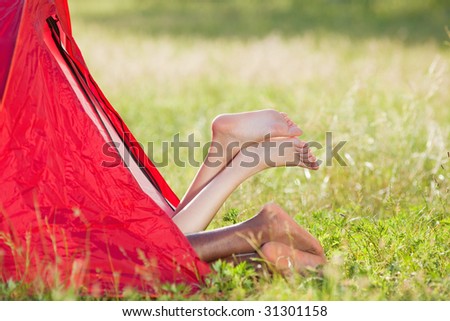 young multiethnic couple lying in tent with feet crossed. Copy space