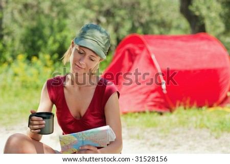 blonde woman sitting near tent and reading map