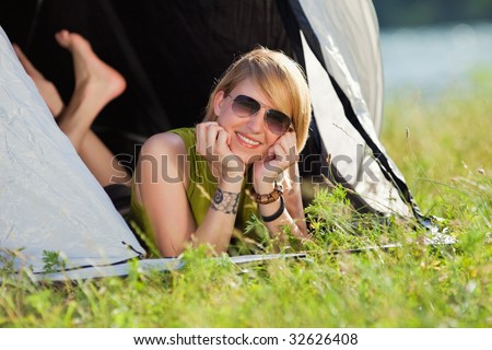 young blonde woman lying in tent with feet crossed.