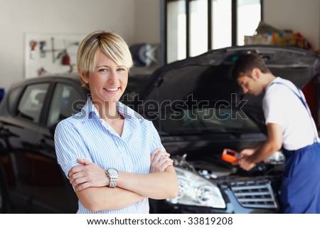 portrait of female client with arms folded in auto repair shop.