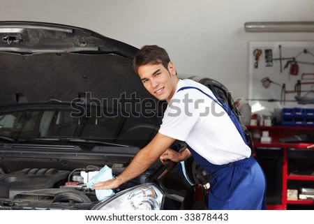 mechanic cleaning car engine and looking at camera