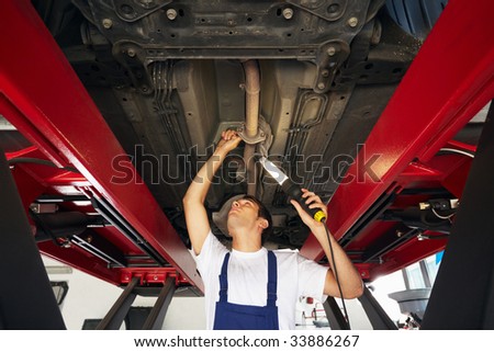 mechanic standing under car engine and holding lamp. Copy space