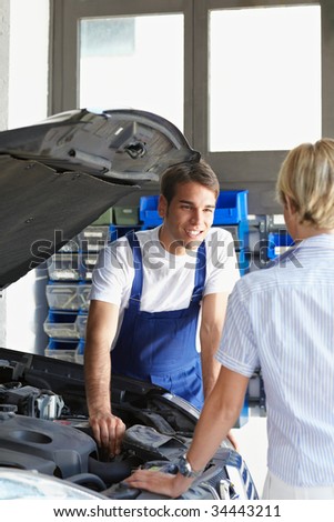 mechanic talking with female client in auto repair shop.