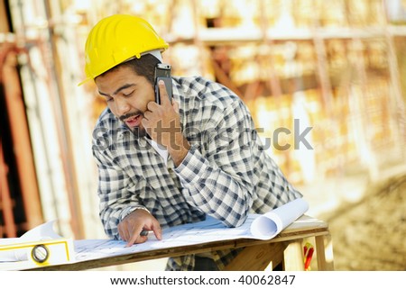 latin american construction worker talking on mobile phone. Copy space