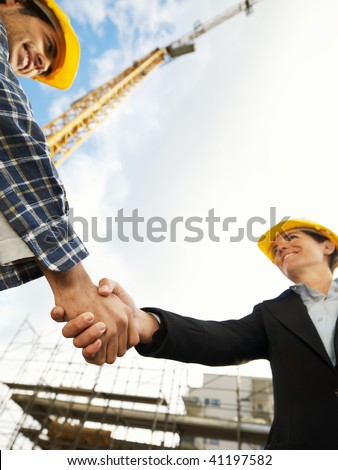 female architect and construction worker shaking hands. Low angle view, copy space