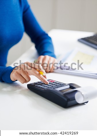 close up of business woman typing on calculator