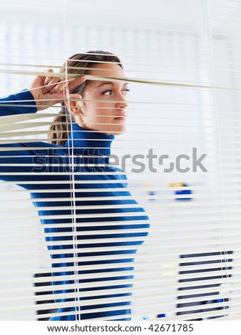 young businesswoman looking through blinds. Copy space