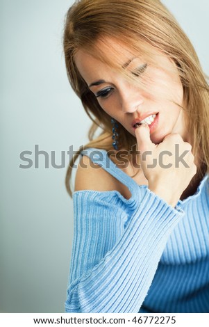 portrait of 30 years old woman biting her fingernails on cyan background. Vertical shape, Copy space
