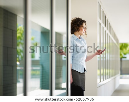 woman standing out of office building and reading emails on mobile phone. Horizontal shape, Copy space