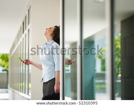 italian business woman standing out of office building and reading emails on mobile phone. Horizontal shape, Copy space
