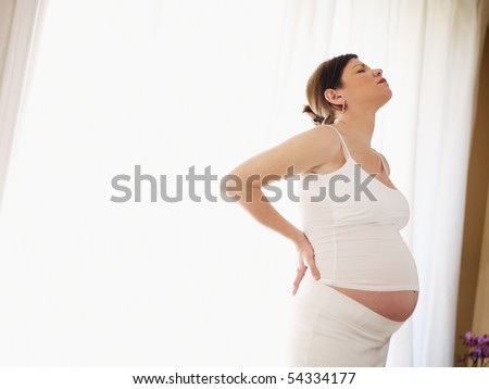 stock photo : italian 7 months pregnant woman massaging her back.