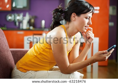 mid adult woman on sofa staring at her mobile phone and biting nails. Horizontal shape, waist up, copy space