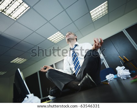 Mature businessman sitting on desk in lotus position. Horizontal shape, full length, Copy space