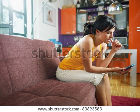 mid adult woman on sofa staring at her mobile phone and biting nails. Horizontal shape, full length, copy space