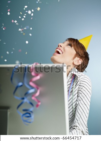 caucasian woman looking at confetti being thrown in office. Vertical shape, side view, waist up, copy space