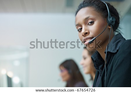 multiethnic group of female customer service representatives talking on the phone, with african woman looking at camera. Horizontal shape, side view, copy space