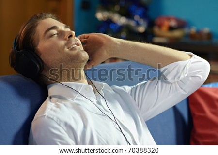 caucasian adult man relaxing on sofa with headphones. Horizontal shape, side view, head and shoulders